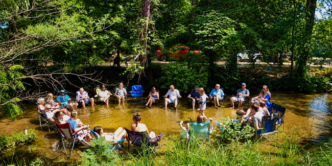Families relaxing together in the creek at White River RV Park & Campground during a summer camping vacation
